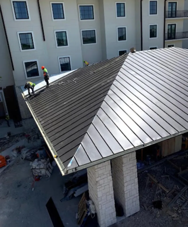Crew installing standing seam metal roof panels on a commercial project in Trinity